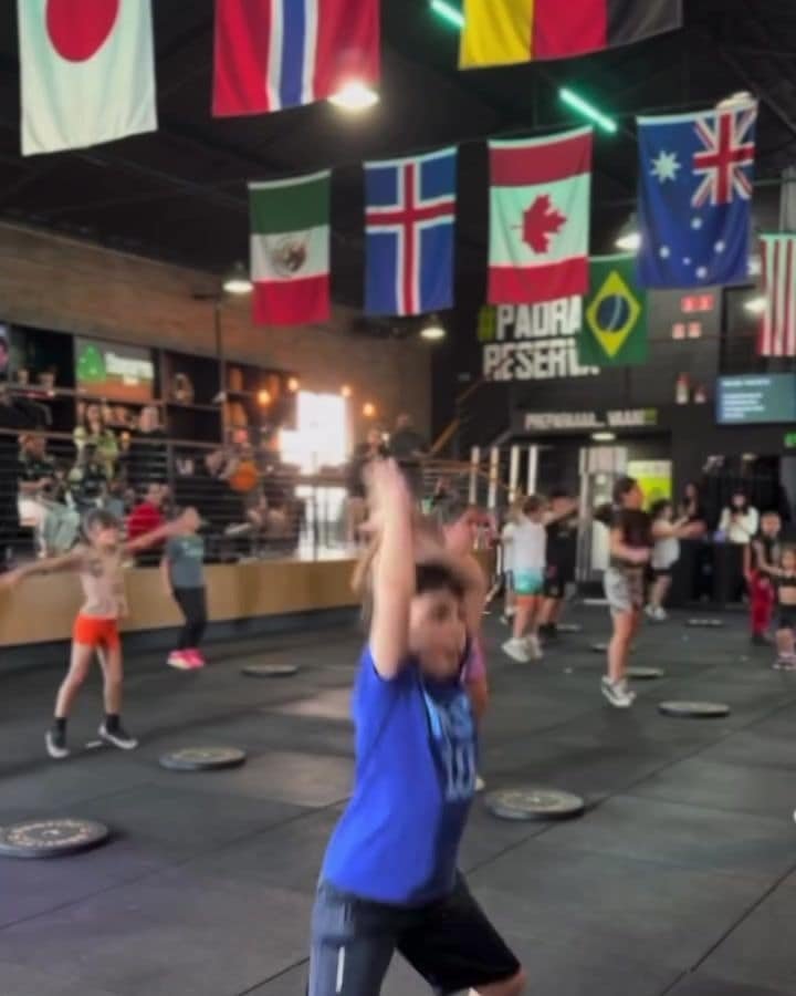 Turma de CrossFit Kids treinando no box com bandeiras ao fundo
